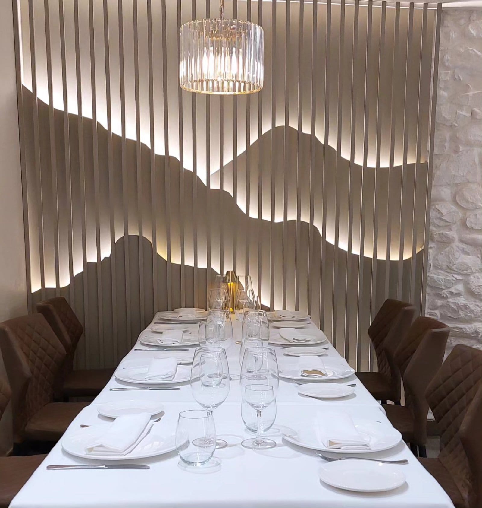 Comedor de La Casuca del Gorbea con la pared de lamas que dibuja la silueta del monte retroiluminada